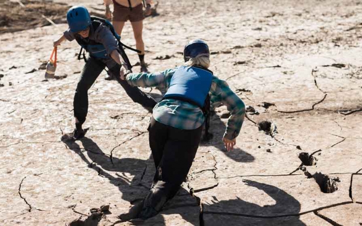 a student helps another who is stuck in mud